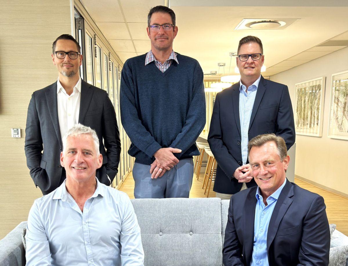 A group of five men in business suits stands together for a photo, celebrating Omnisient's $7.5 million Series A funding success.